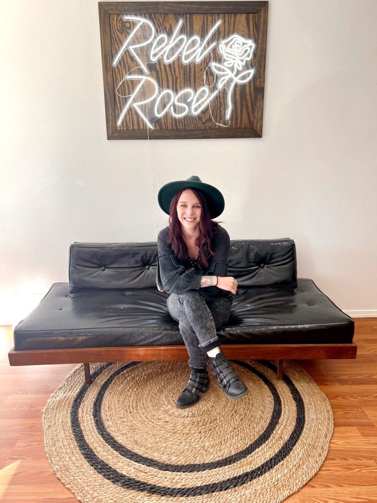 Brittney Miller owner of Rebel Rose sitting on a black couch